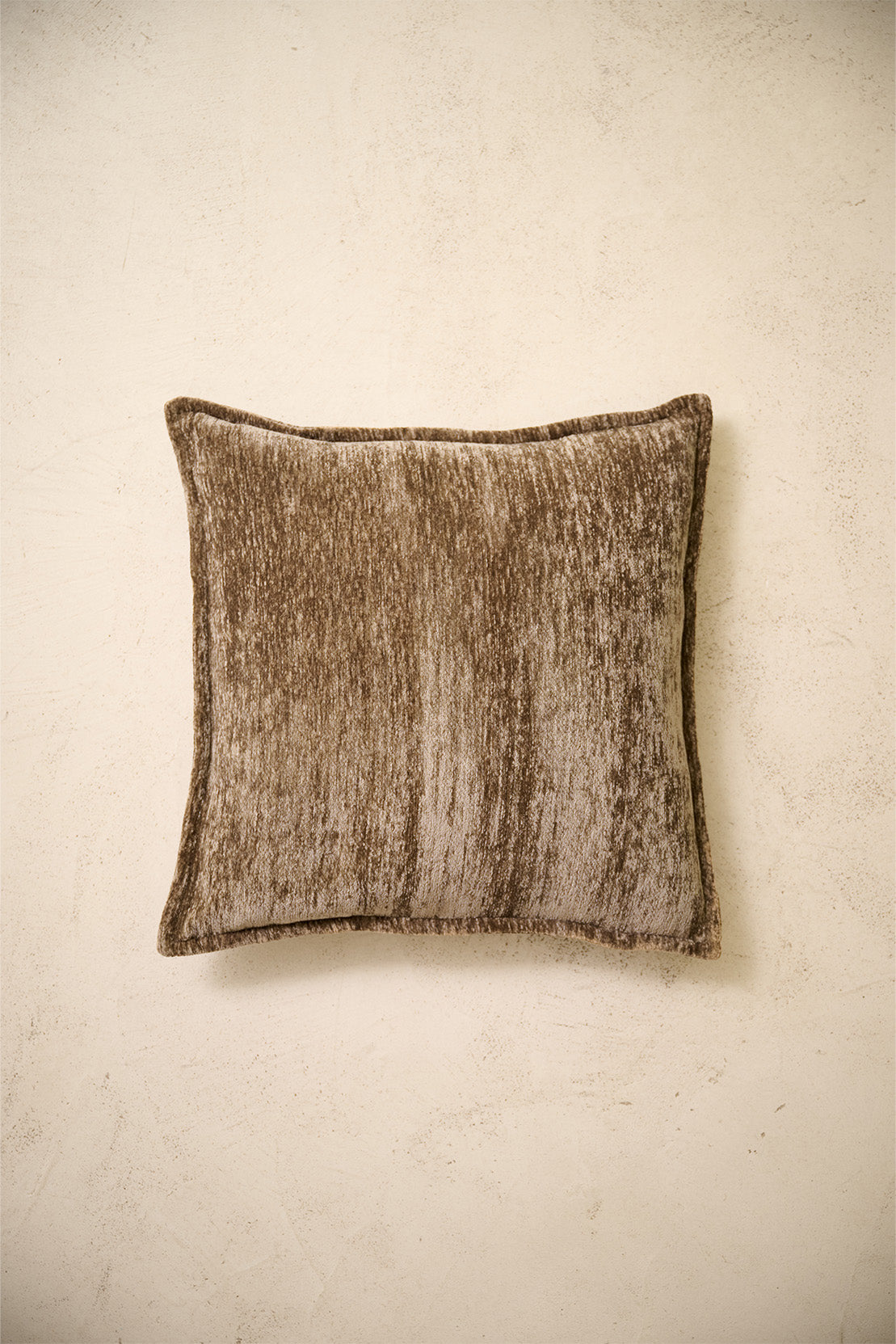 coussin carré BLIZZARD en chenille brun chiné à bord plat, sur un mur en enduit crème