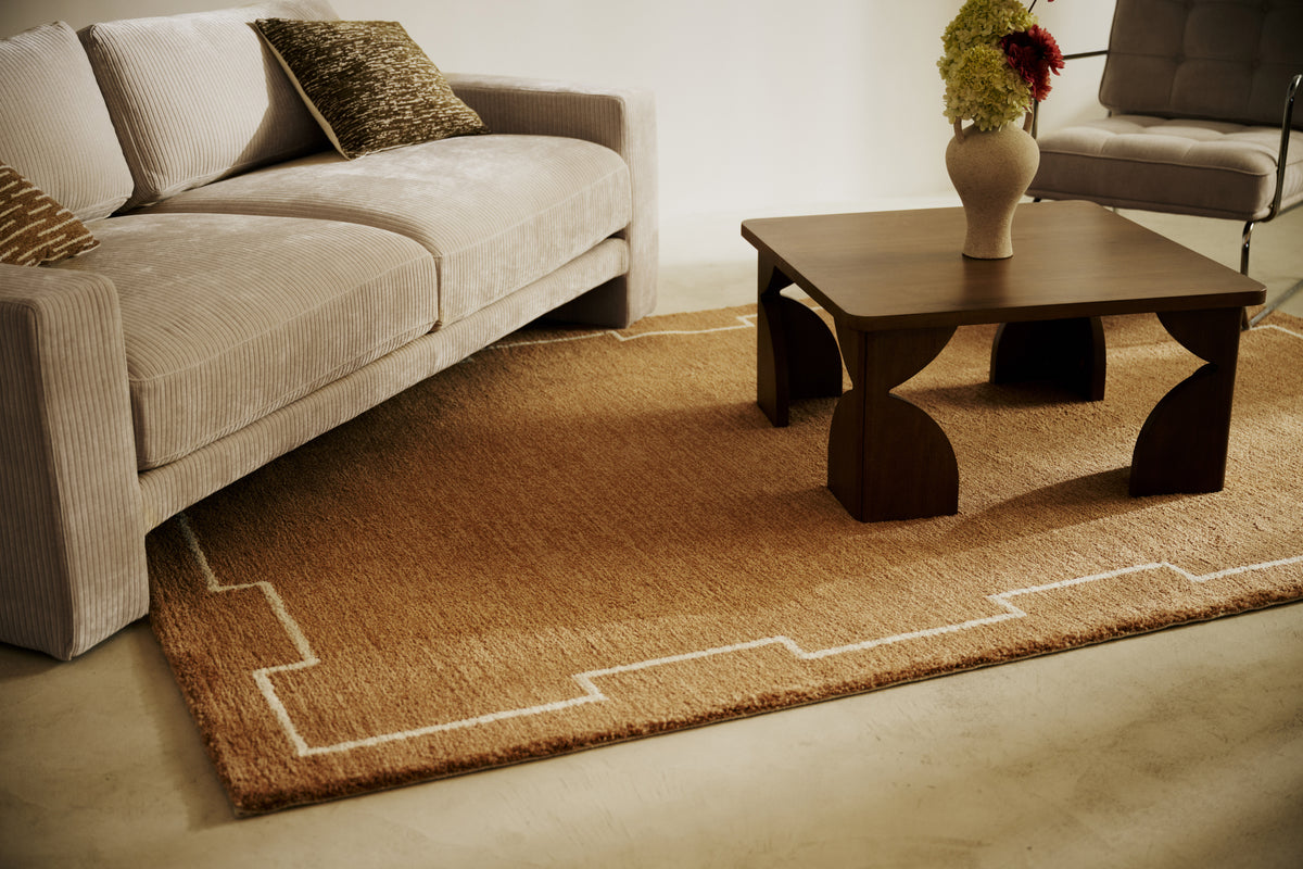 salon avec tapis Crest caramel, canapé en velours côtelé écru et table basse en bois foncé