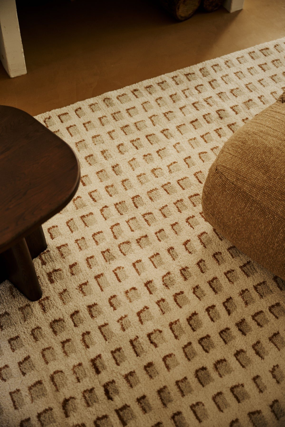 salon à cheminée avec tapis Weave écru, fauteuil chiné ocre et table basse en bois