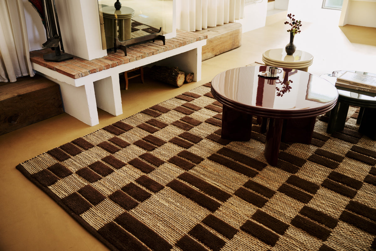 tapis de salon Saxton à damier de jute et laine brune sous des tables basses laquées