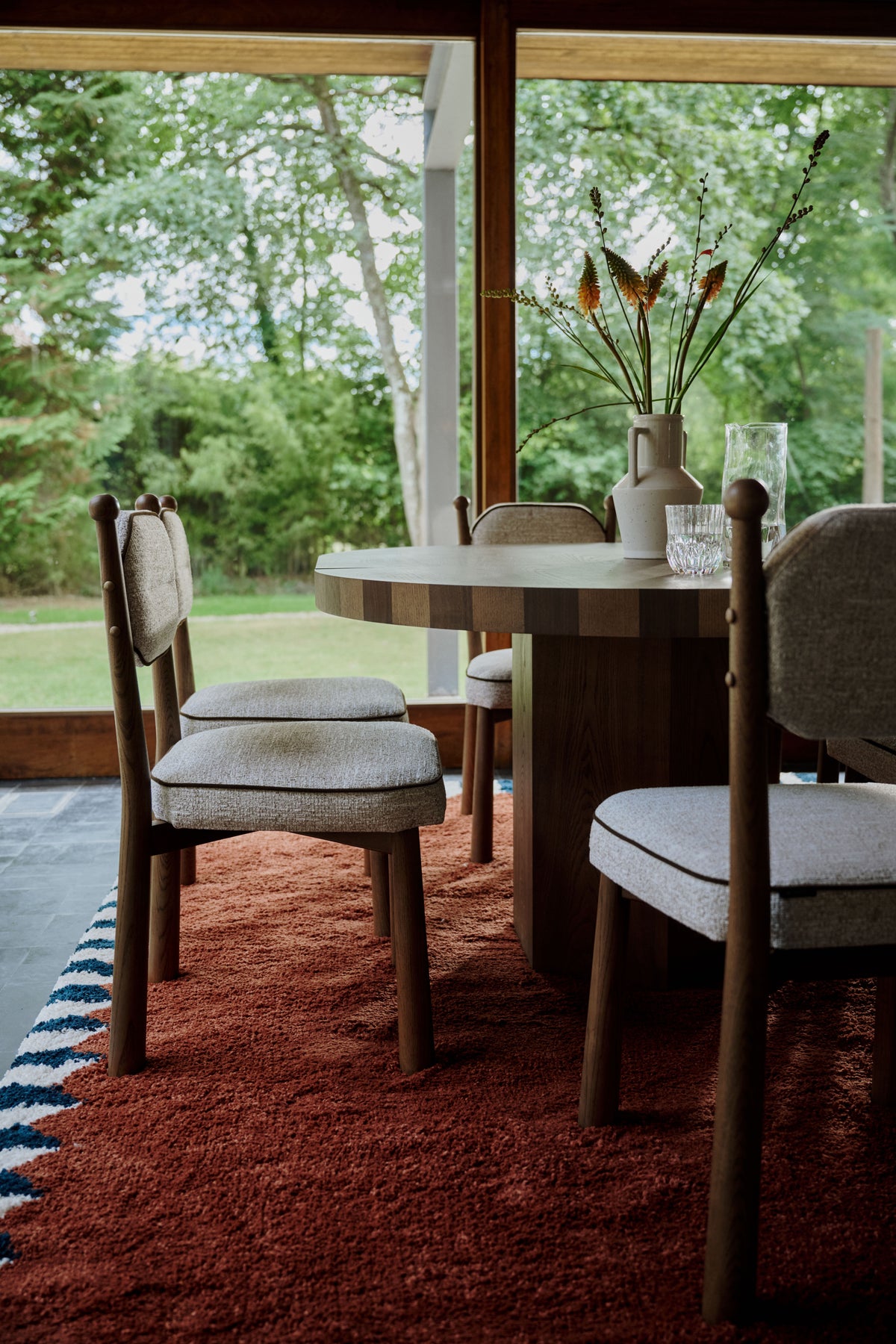 six chaises Anna en tissu chiné beige autour de la table ronde Modanata en chêne