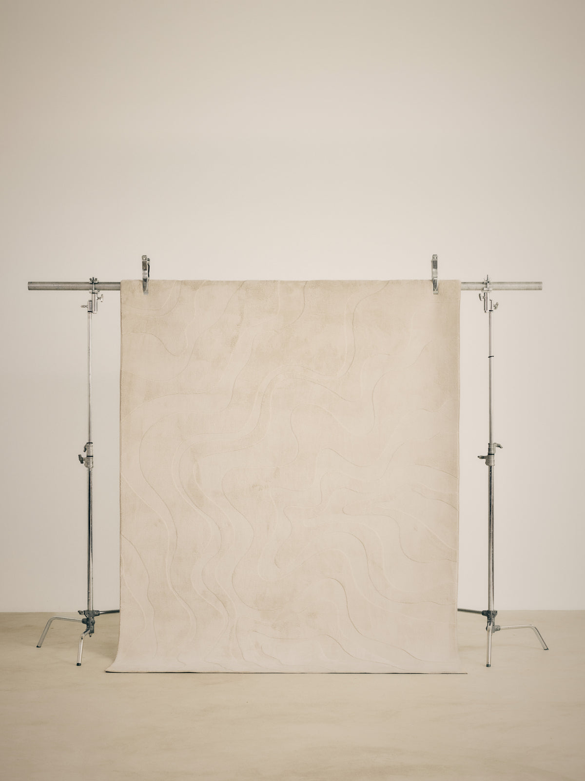 tapis de salon Ikat écru à lignes ondulantes en relief suspendu sur un portant de studio