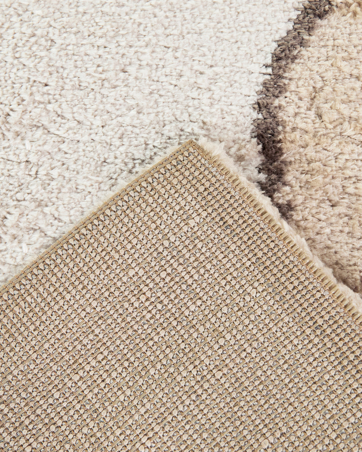 coin replié du tapis TIDAL, hauteur du velours écru et envers tissé beige et gris