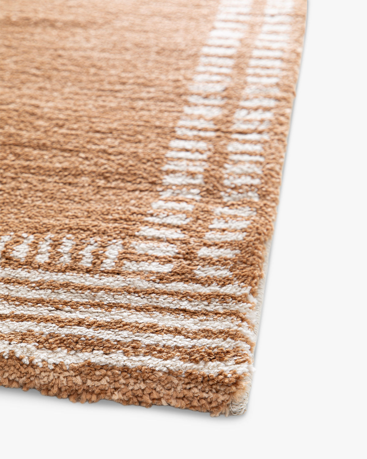 gros plan sur l'envers tissé et la lisière surjetée écrue d'un tapis de salon Haven caramel