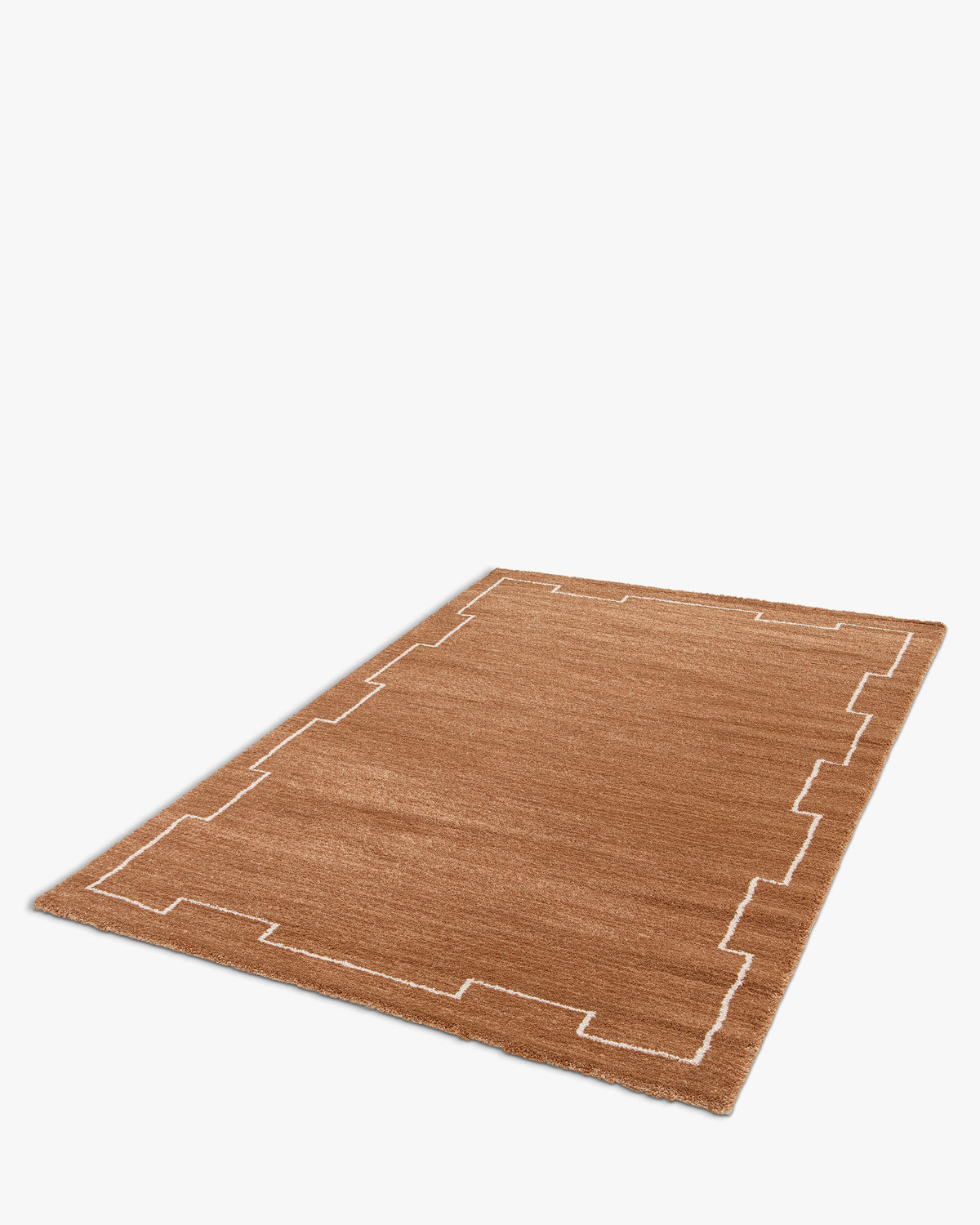 tapis de salon Crest en polypropylène terracotta à bordure graphique écrue - vue de trois quarts