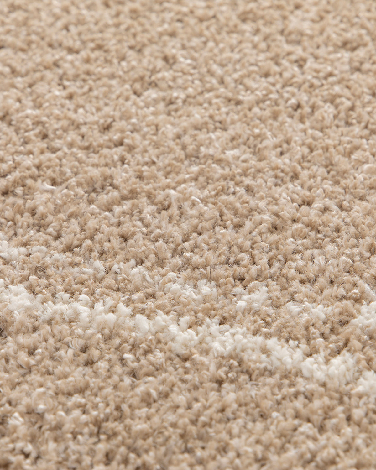 gros plan sur le double trait écru tracé dans le velours beige d'un tapis Estero