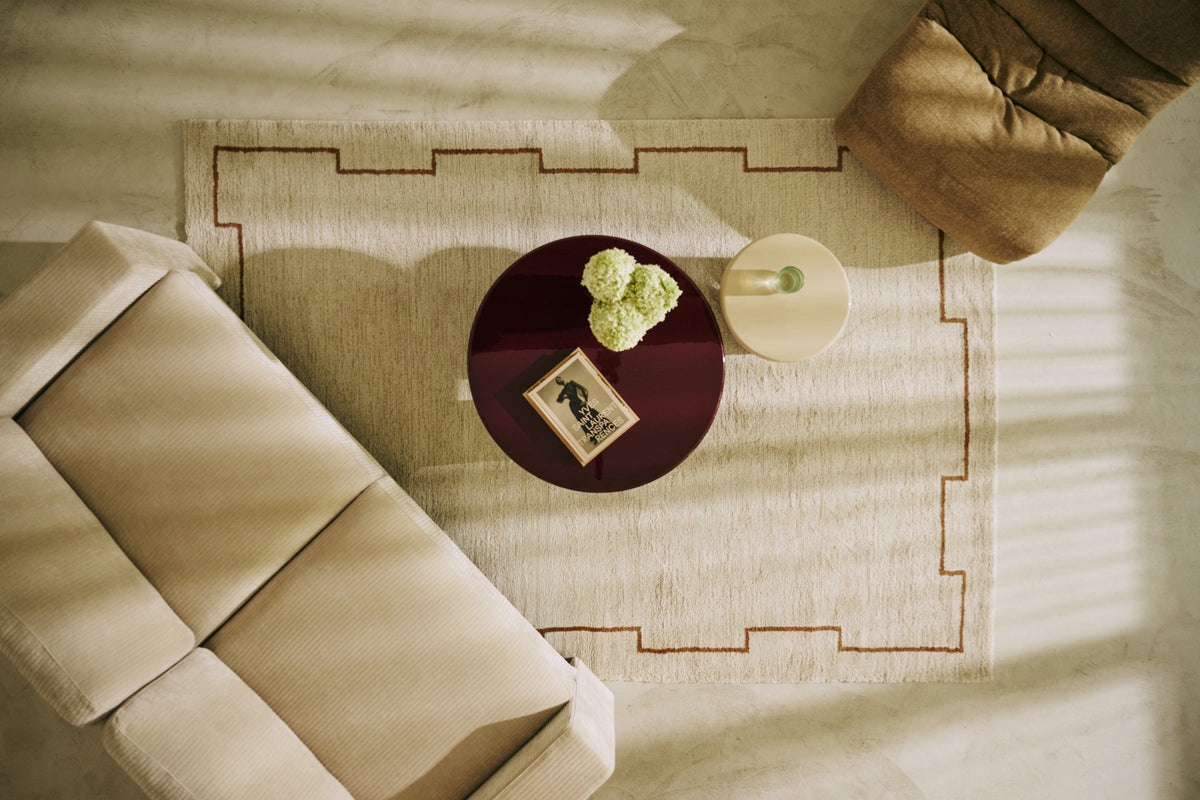salon vu de dessus avec tapis Crest beige, canapé en velours côtelé et table basse ronde