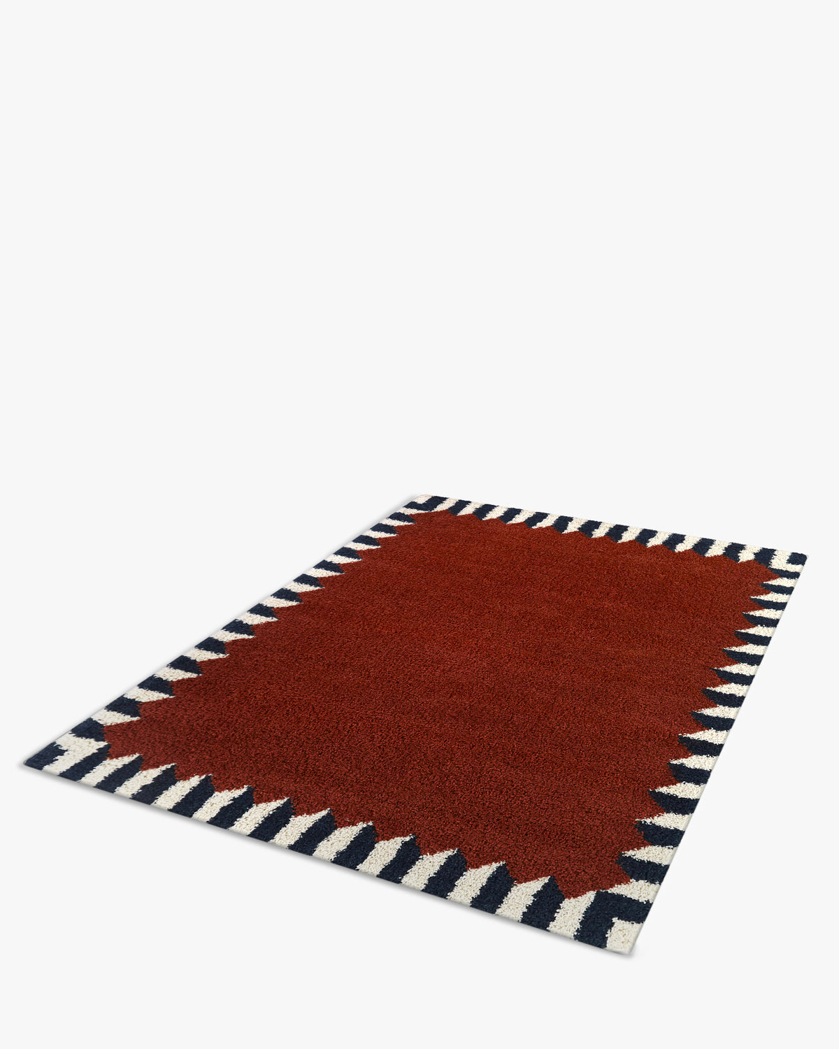 tapis ARDMORE rouge brique bordé de triangles bleus et écrus, posé à plat vu de côté