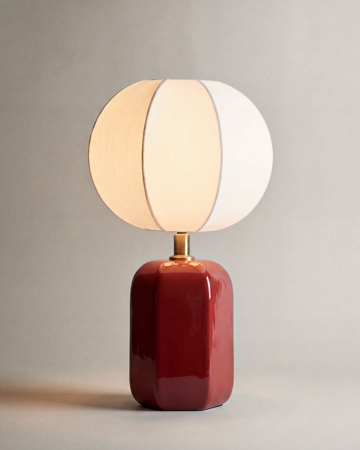 lampe de table AGATHA allumée, pied en céramique rouge et abat-jour en lin écru à lobes