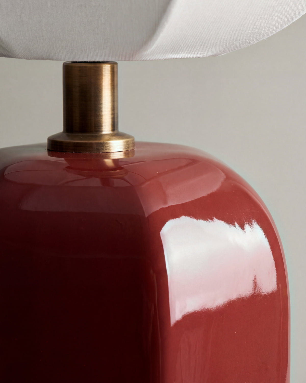 gros plan sur la céramique rouge brillante et la douille en laiton de la lampe AGATHA
