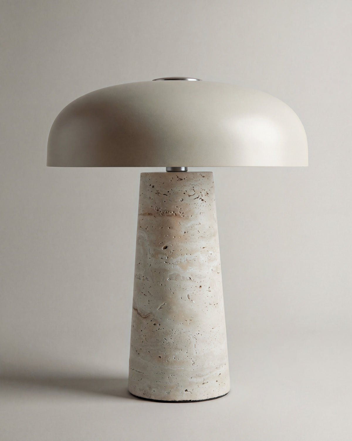 lampe de table AMANITA allumée, sa lumière descend sous le dôme et dore le travertin