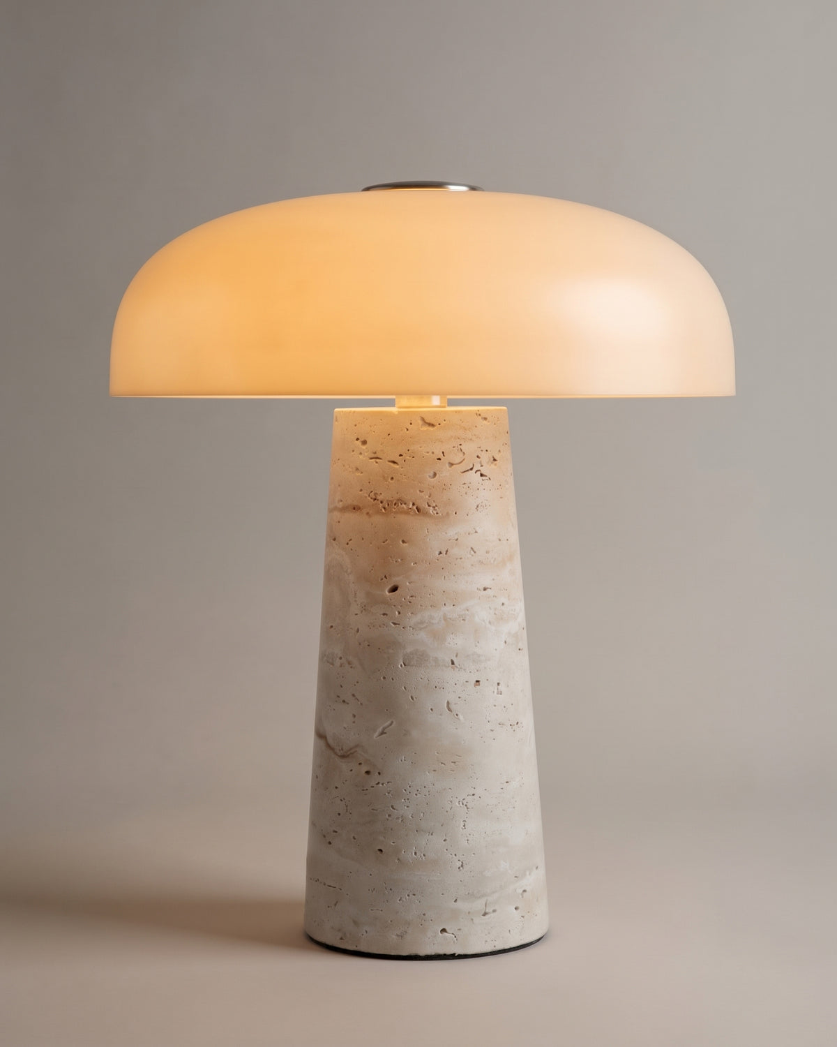 lampe de table AMANITA allumée, dôme en verre opalin sur un pied conique en travertin