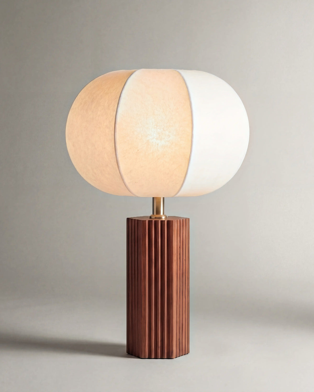 lampe de table AVAIA allumée, pied cannelé en noyer et abat-jour en papier blanc à lobes