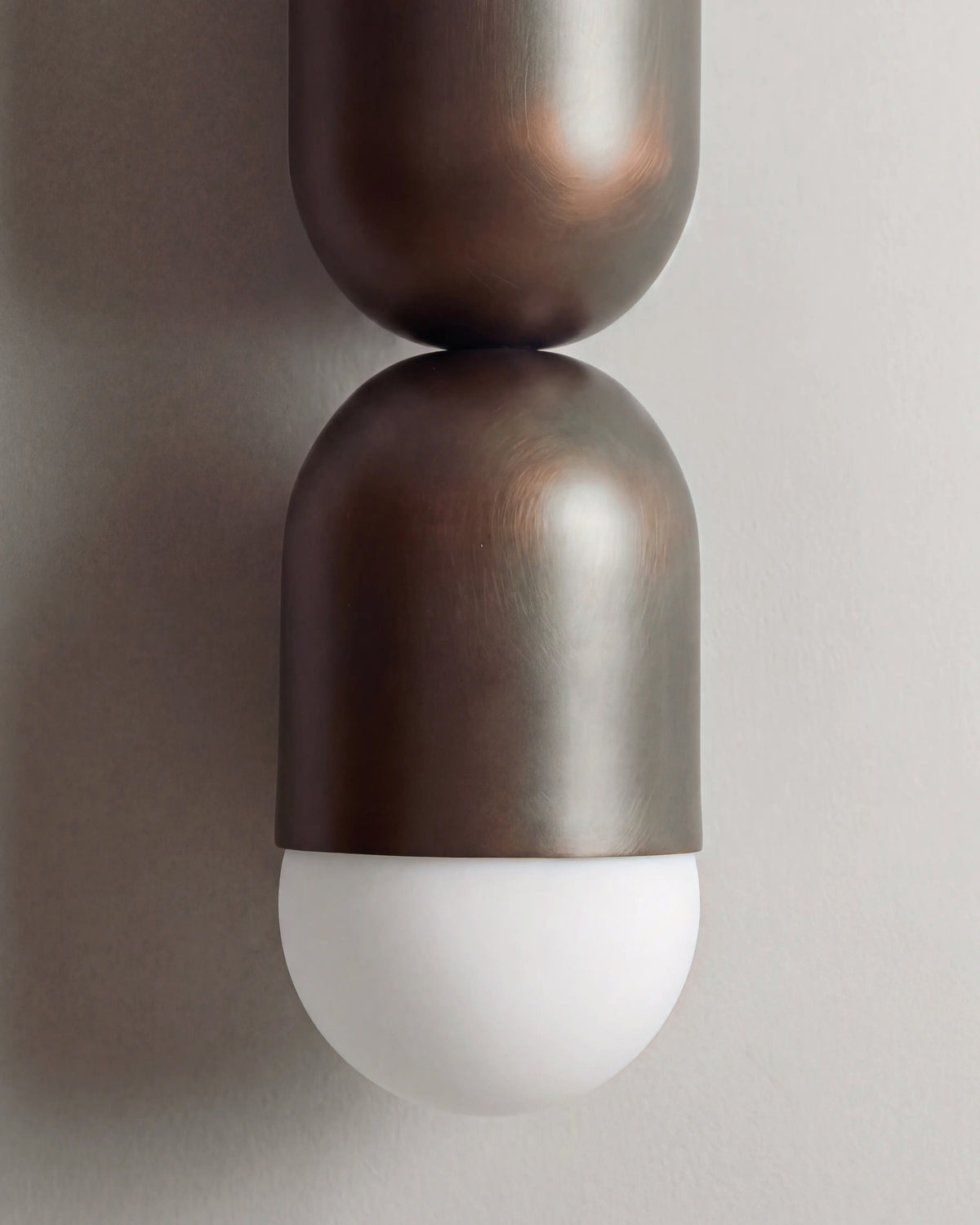 gros plan sur les volumes arrondis en métal bronze et le globe opalin de l'applique AYOKA