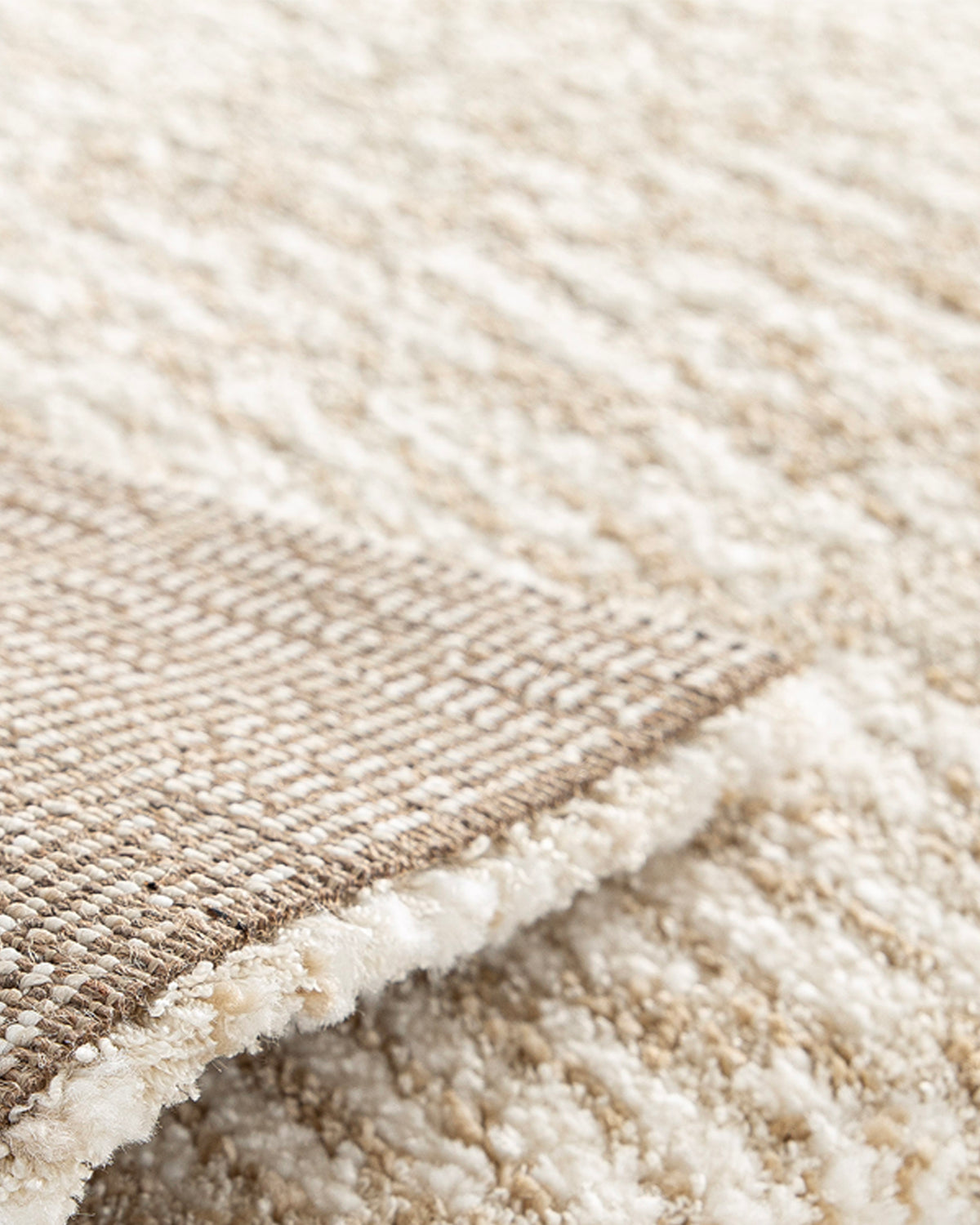 gros plan sur l'envers tissé beige et la lisière d'un tapis Cortex écru en grand format