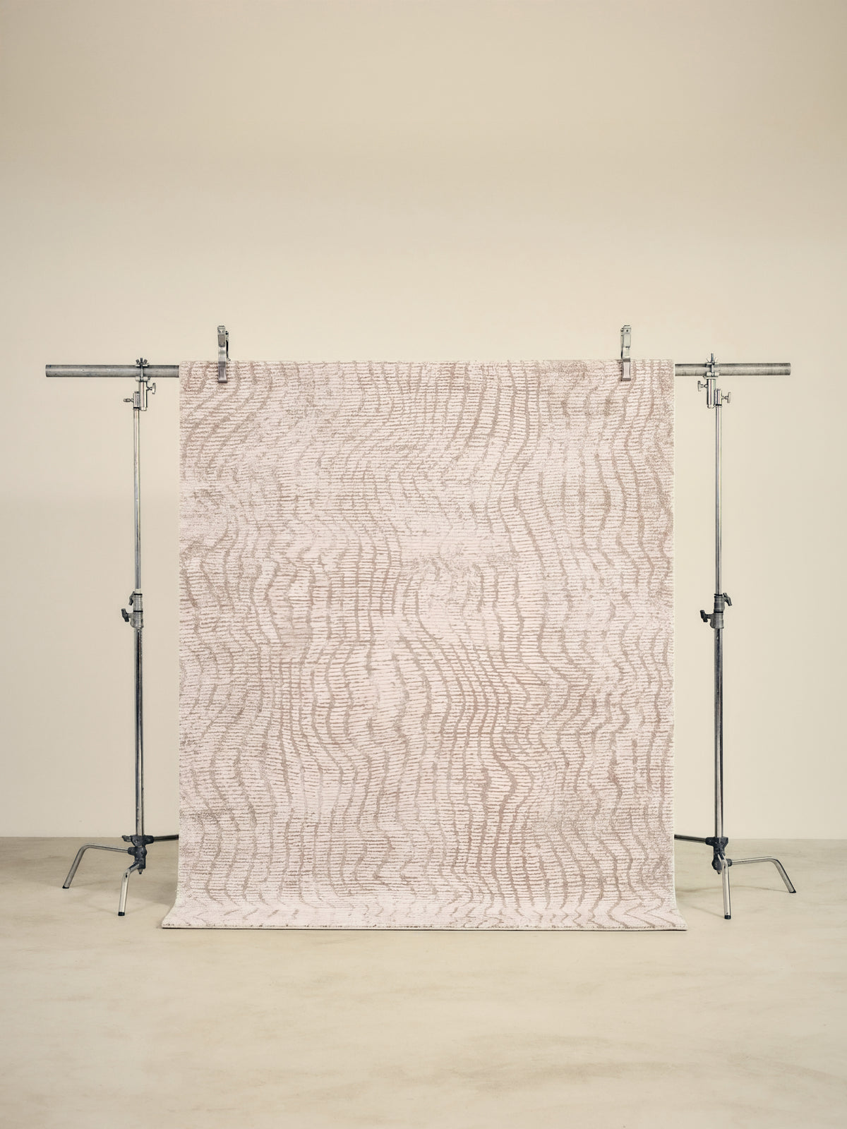 tapis CORTEX grand format, écru à ondulations beige en relief, sur un portant de studio