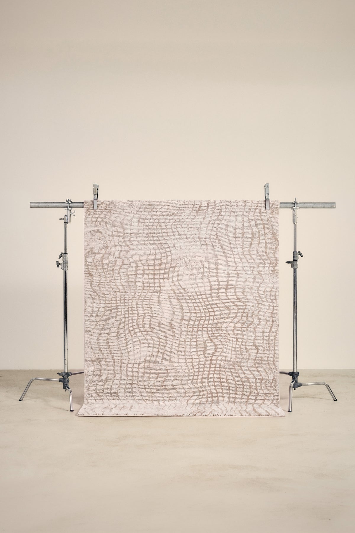 tapis CORTEX petit format, écru à ondulations beige en relief, sur un portant de studio