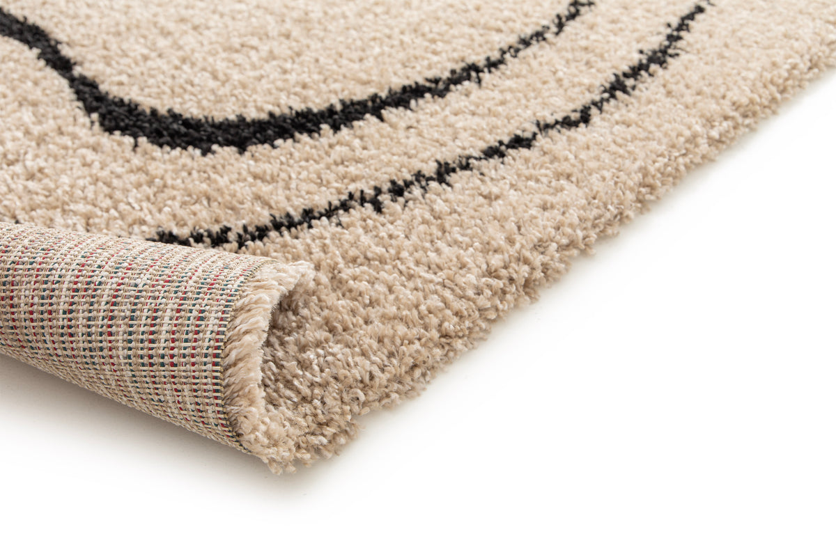 coin replié du tapis DRIFT, épaisseur des mèches beige et envers tissé multicolore
