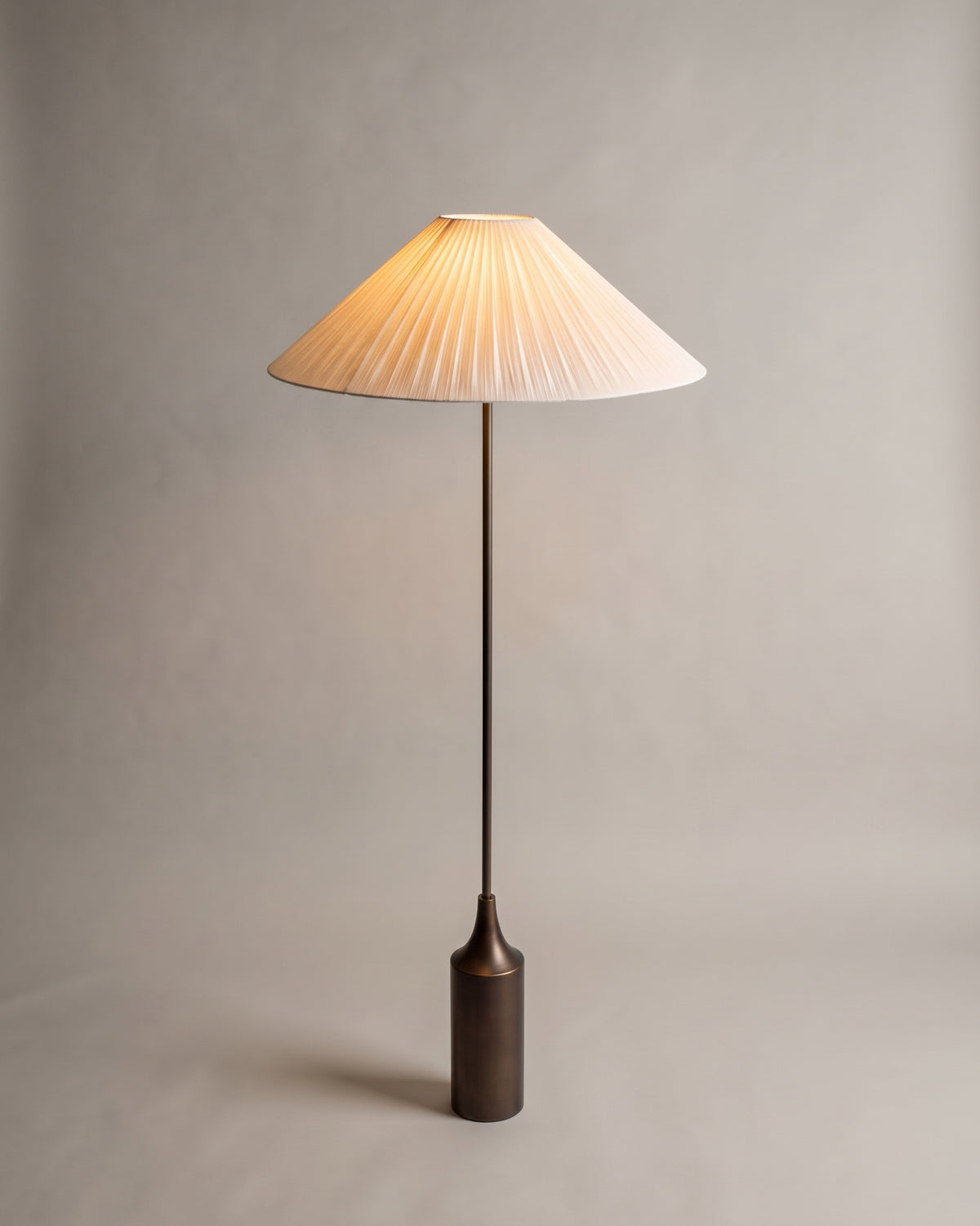 lampadaire KENSINGTON allumé, abat-jour plissé écru sur une base bouteille en bronze