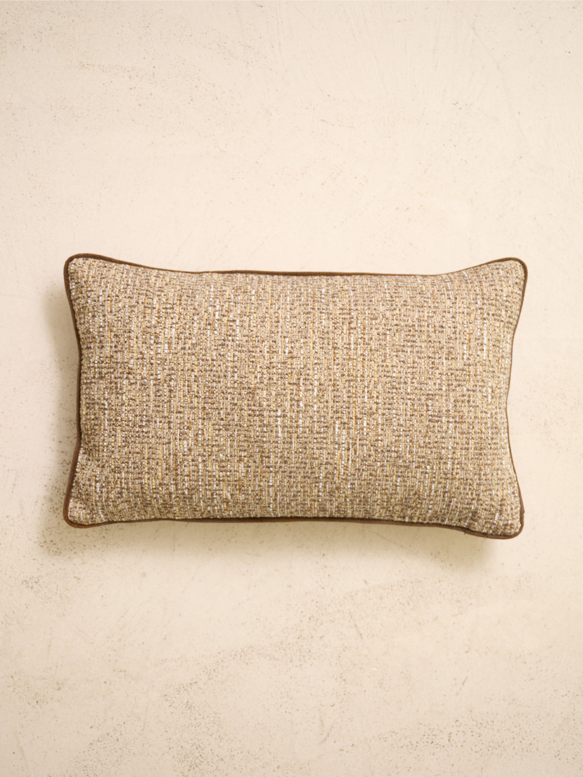 coussin rectangulaire LODGE en tweed beige et marron posé sur un mur en enduit crème