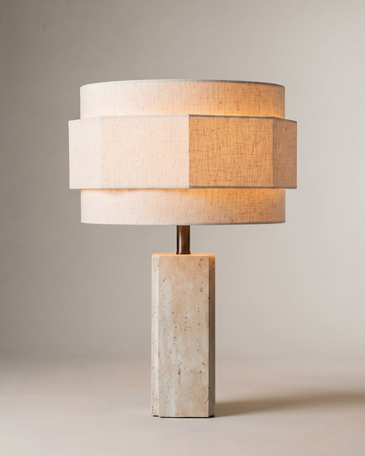 lampe de table MINDY allumée, pied en travertin et abat-jour en lin écru à trois étages