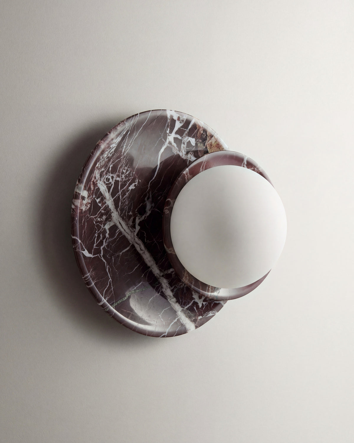 applique murale ORBE en marbre rouge veiné de blanc et globe opalin, éteinte vue de face