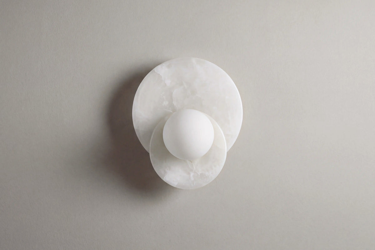 applique murale ORBE en albâtre blanc, disque et globe décentré, éteinte sur mur clair