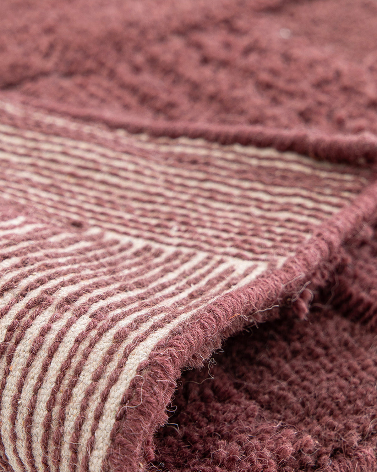 gros plan sur l'envers tissé à rayures bordeaux et écrues d'un tapis de salon Woven
