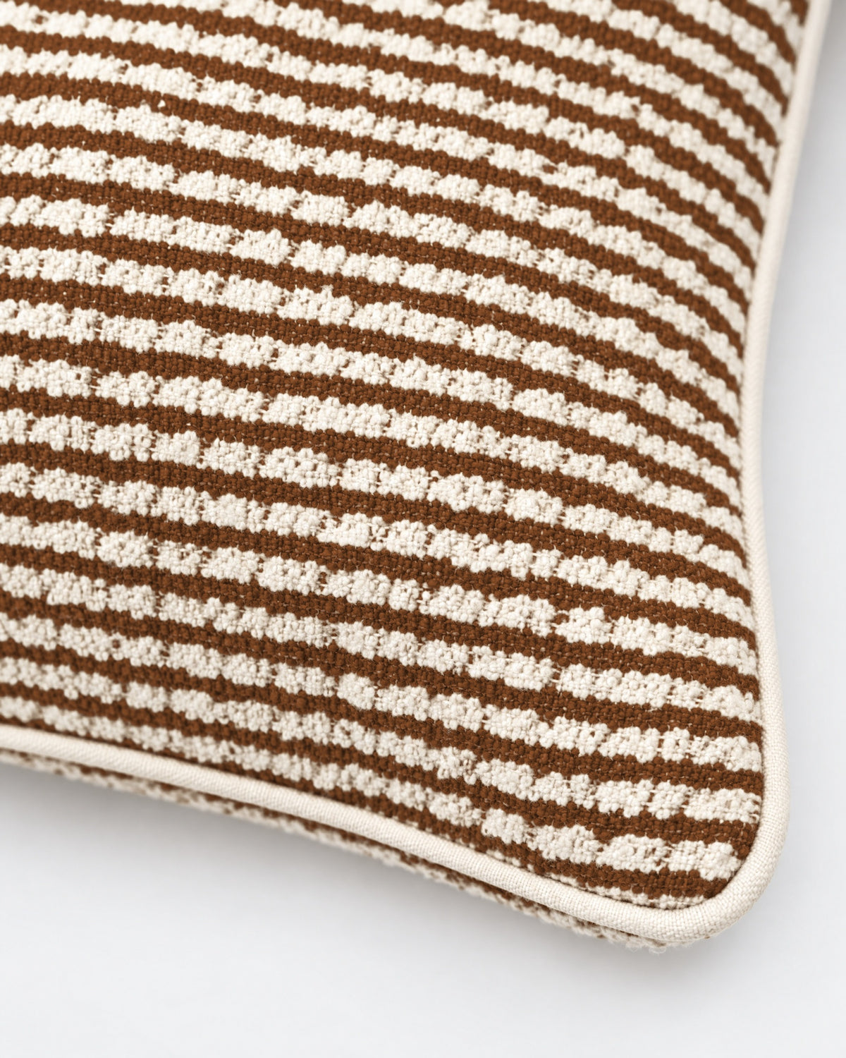 gros plan sur le tissage bouclé et les rayures marron du coussin LODGE écru à passepoil