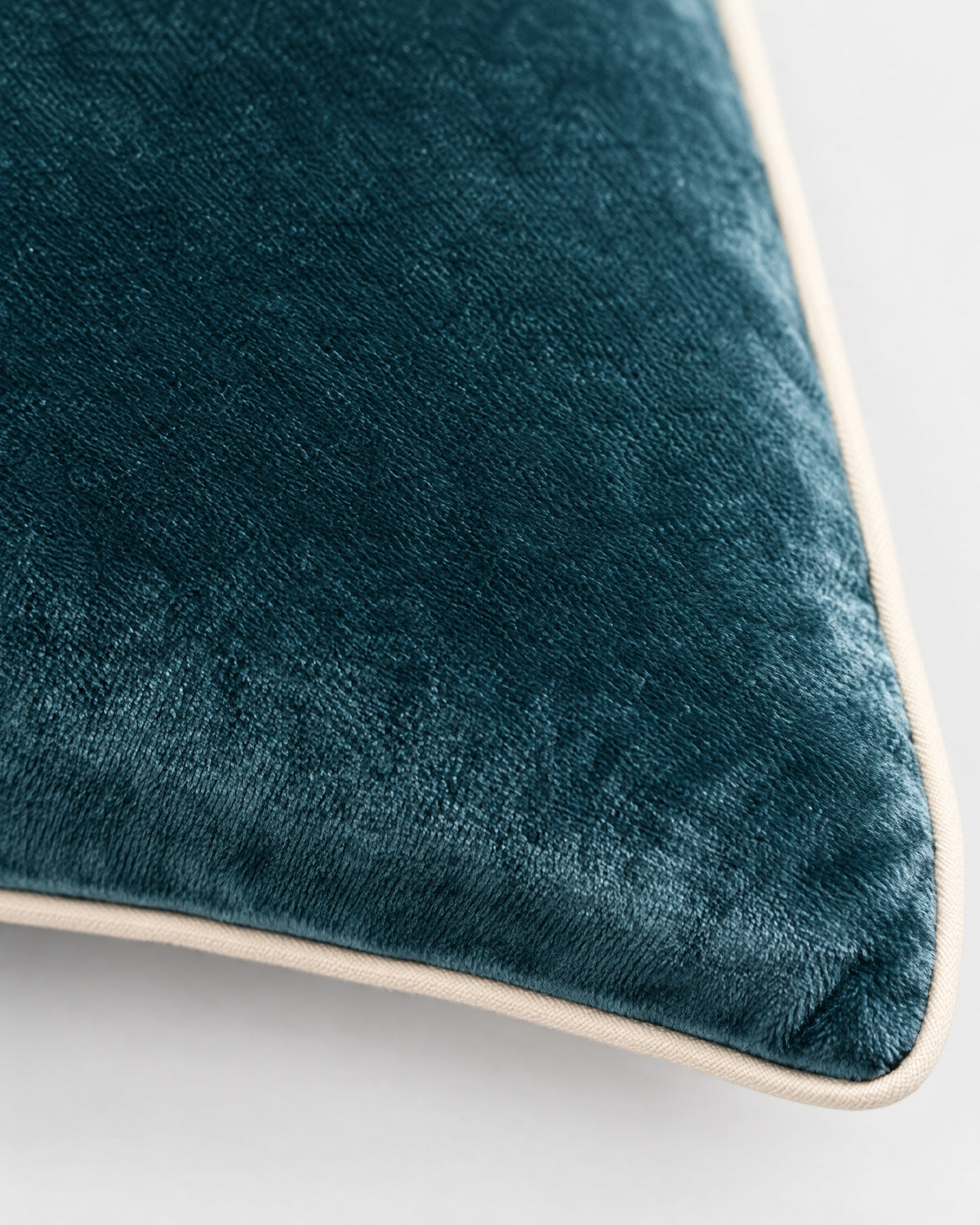 gros plan sur le passepoil écru et la texture du velours bleu canard du coussin LODGE