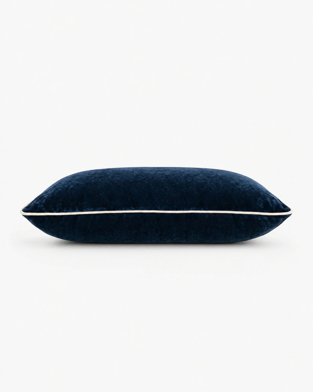 coussin rectangulaire LODGE en velours bleu nuit vu de profil, passepoil écru sur la tranche