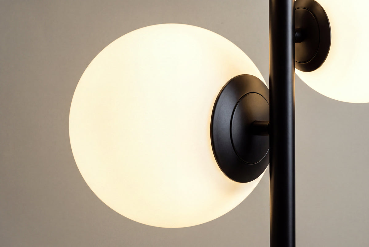 gros plan sur un globe opalin allumé et sa monture en métal noir du lampadaire SKULL