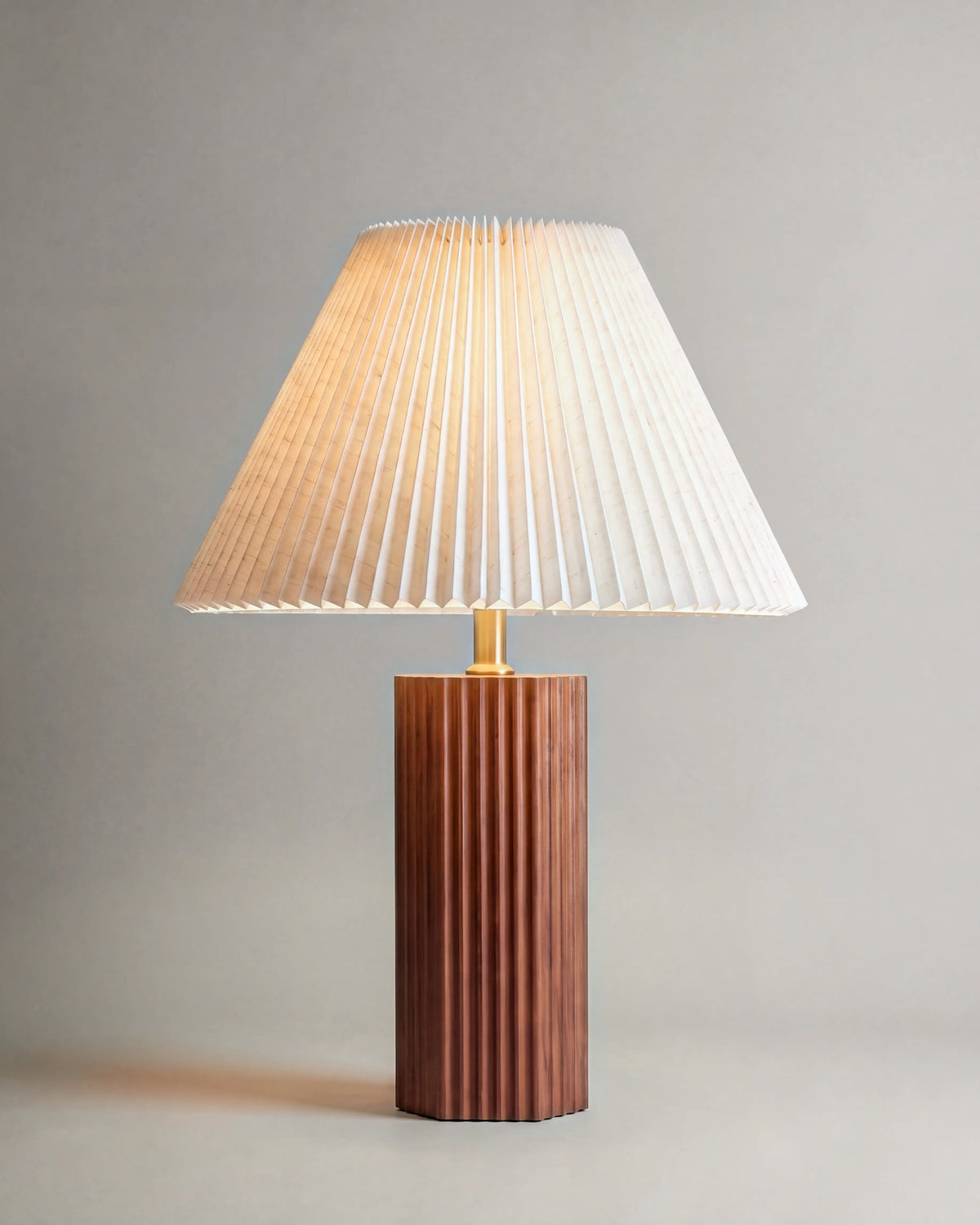 lampe de table SOE allumée, pied cannelé en noyer et abat-jour conique plissé écru