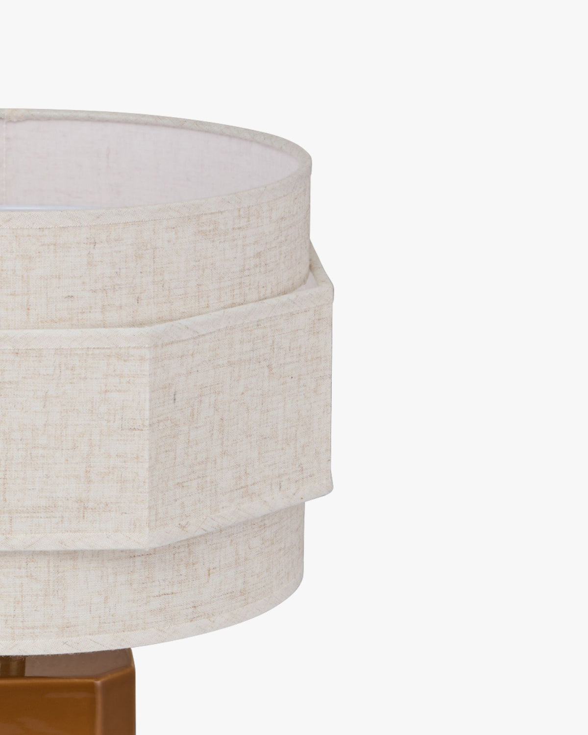 Abat-jour en lin écru de la lampe Eira vu de trois quarts au-dessus du socle en céramique caramel