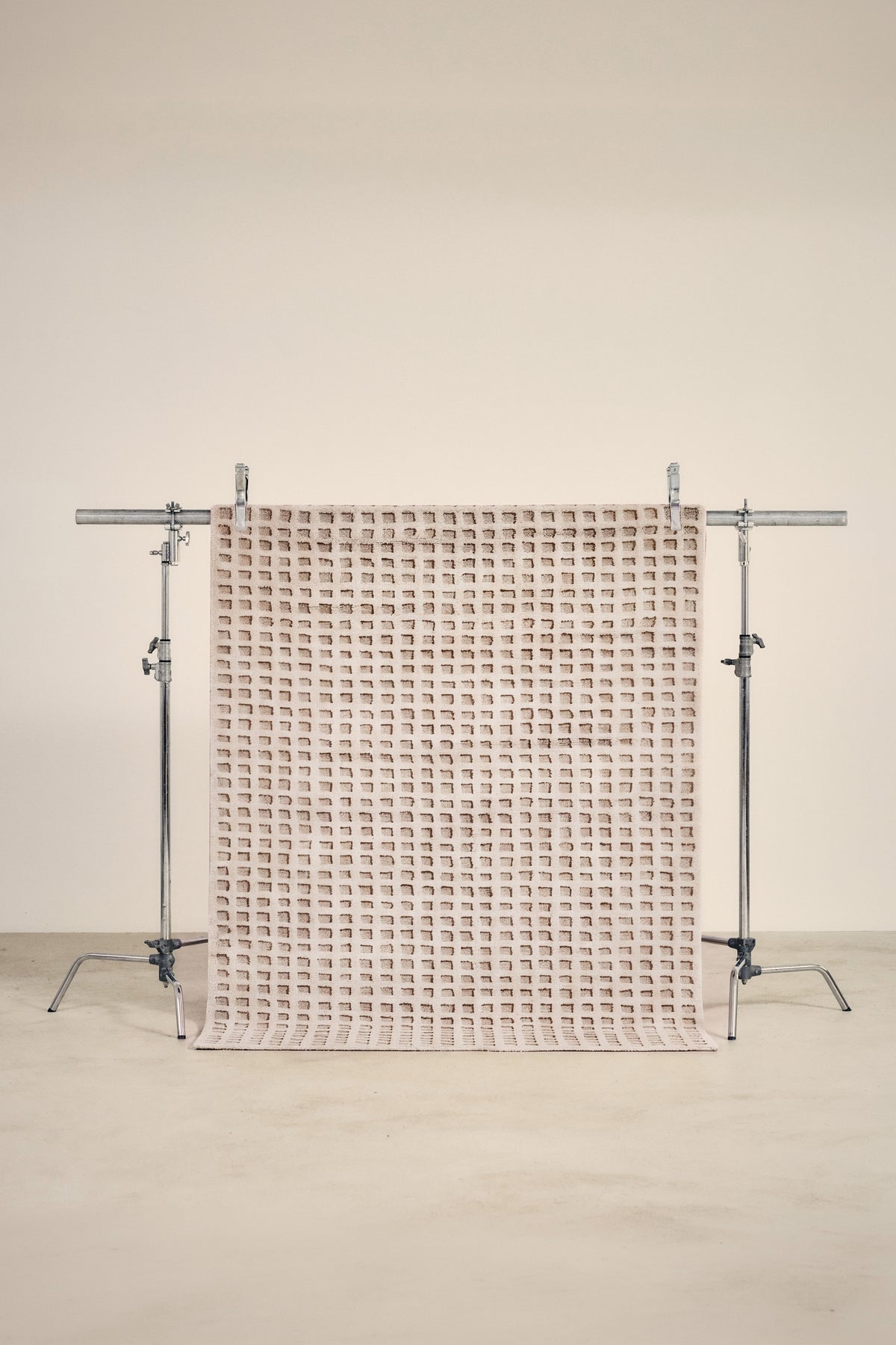tapis WEAVE petit format, écru à damier de carrés en relief, sur un portant de studio