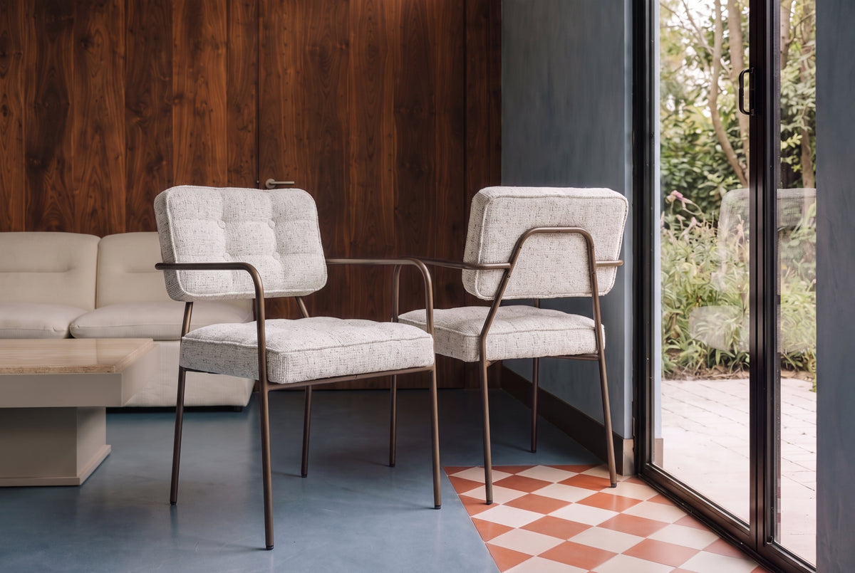 chaises de salle à manger Orea en tissu chiné écru et structure tubulaire dans un salon vitré