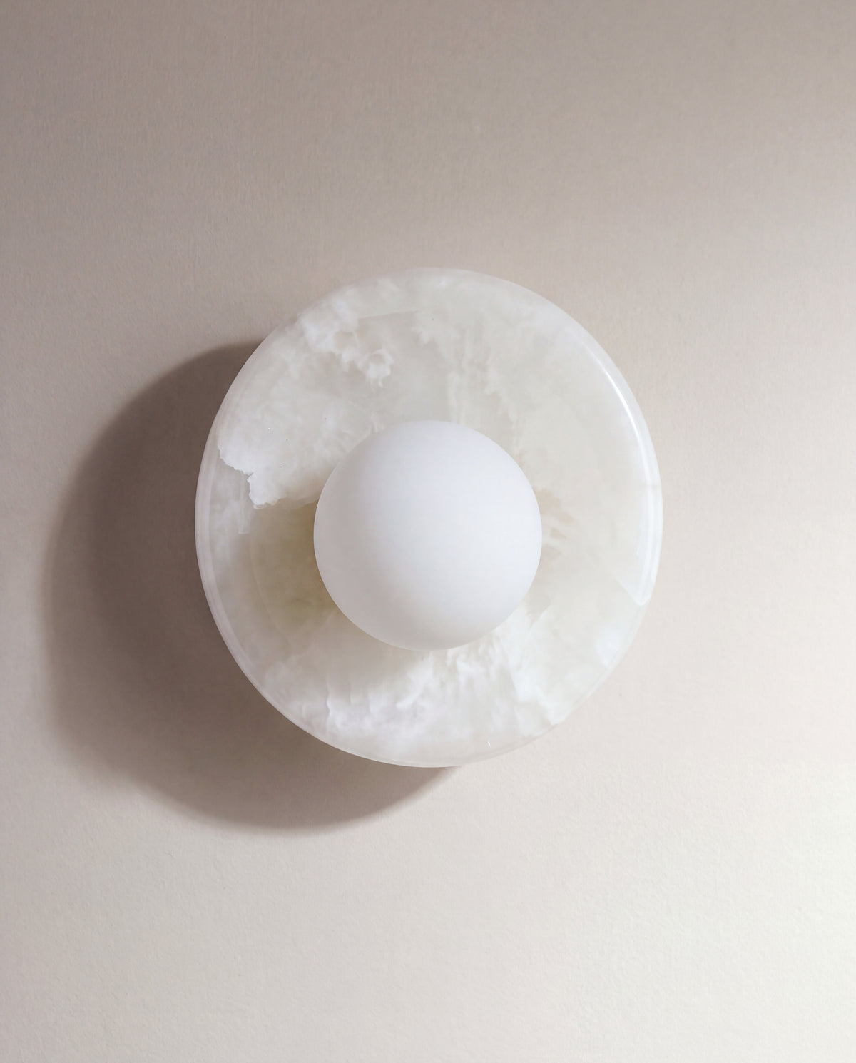 applique murale ORBE, disque en albâtre blanc et globe opalin centré, éteinte de face